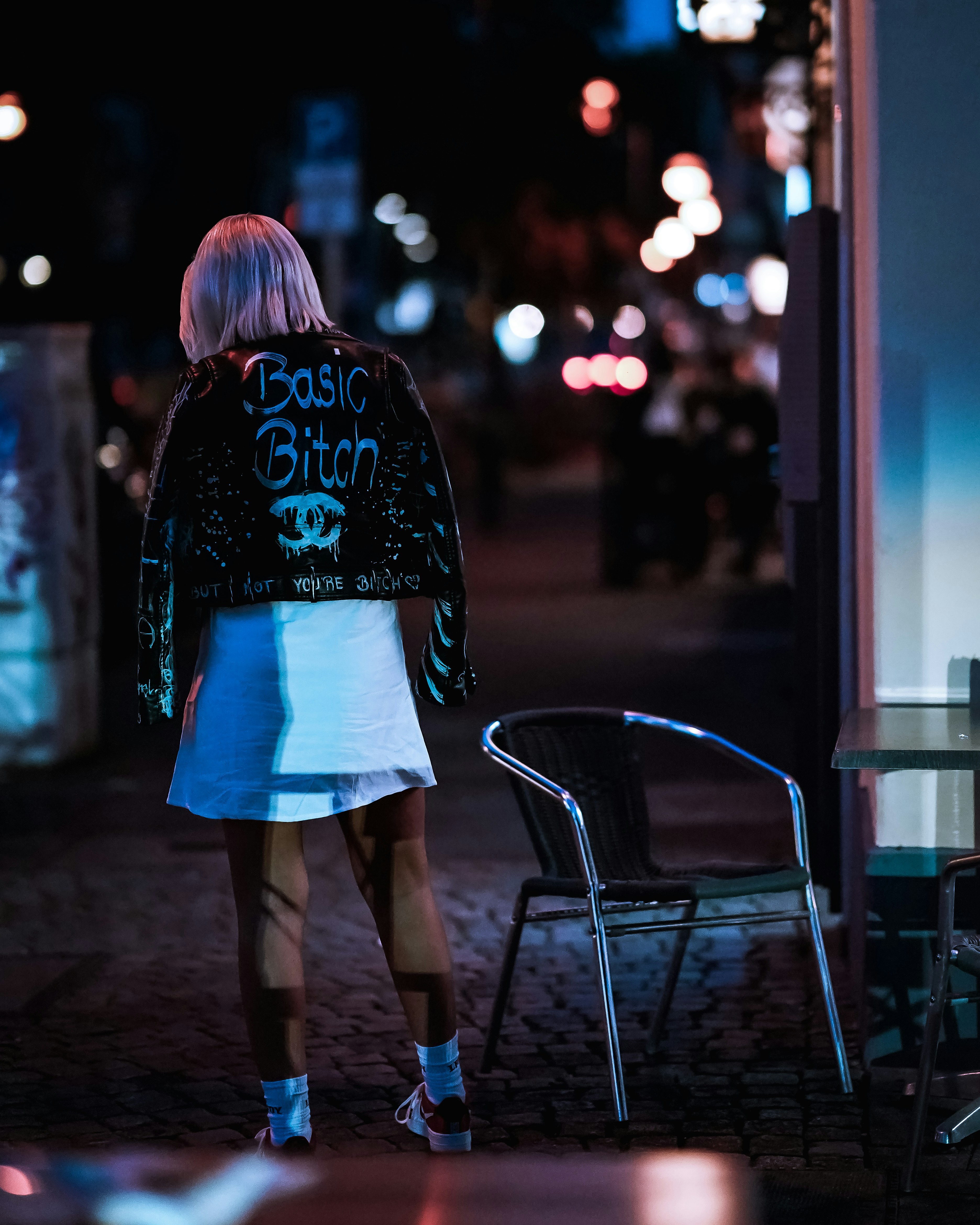 woman in white mini skirt standing near glass window